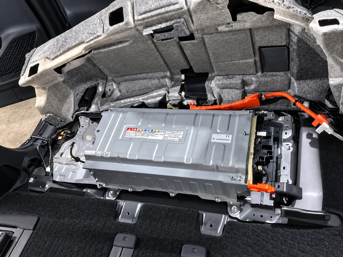     「ハイブリッドバッテリー交換作業  診断結果をもとに、今回はリビルトハイブリッドバッテリーへ交換します。  ヴォクシー ハイブリッドのバッテリーは車内床下付近に搭載されているため、シートや内装部品を取り外してバッテリー本体へアクセスします。  高電圧回路を安全に遮断したうえで、各コネクターや配線、固定金具を確認しながら慎重に取り外します。バッテリー交換のため、シートや内装部品を取り外していきます。」
